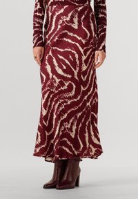 Burgunderrote Maxiröhre mit cremefarbenen Tigerstreifen, fließender Stoff, tailliertem Bund, kombiniert mit dunkelbraunen Knöchelbooten mit einer breiten Absatzhöhe.