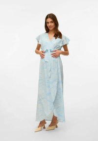 Svetlo modra obleka s cvetličnim vzorcem, kratkimi volančastimi rokavi, kravato v pasu in dolgotrajno silhueto. Oblečena z bež čevlji.