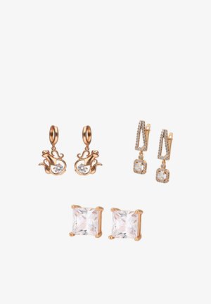 Tre coppie di orecchini color oro: a forma di teiera con pietre chiare, pendenti geometrici con piccoli cristalli e a perno con pietra quadrata taglio chiaro.