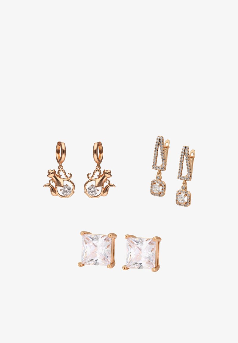 Trzy pary kolczyków w złotym odcieniu: w kształcie czajnika z przezroczystymi kamieniami, geometryczne wiszące z małymi kryształkami oraz kolczyki z kwadratowymi przezroczystymi kamieniami.