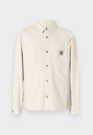 Gaiši brūns, garām piedurknēm krekls-jaka ar pogām priekšā, divām krūšu kabatām, sudraba detaļām un Carhartt logos uz kreisās kabatas.