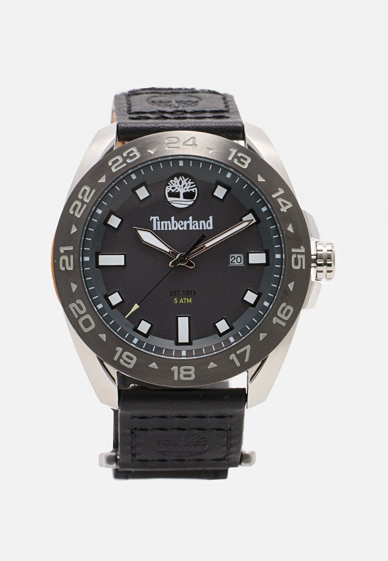 Reloj Timberland negro con caja de acero inoxidable, pantalla analógica, marcadores de hora plateados y blancos, y correa de cuero negro con logotipo estampado.