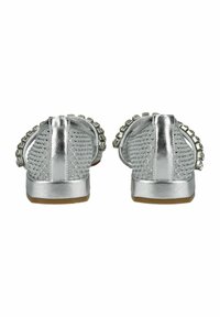 Le scarpe slip-on argentate in metallo presentano una texture intrecciata, dettagli con borchie e una suola piatta con un leggero tacco, progettate per il comfort e la facilità di utilizzo.