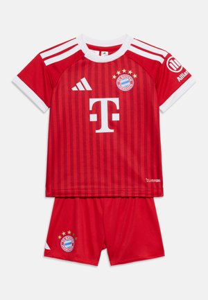 Czerwony strój piłkarski FC Bayern Monachium z białymi paskami, logo sponsorów, herbem klubu z gwiazdkami na koszulce i spodenkach oraz metką technologii "Climacool".