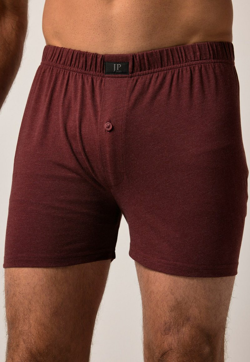 Boxer in cotone bordeaux con cintura elastica e chiusura a bottone singolo. Tessuto liscio e design aderente.