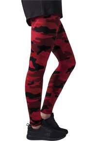 Røde camo leggings i strækbart materiale med sorte detaljer. Designet inkluderer irregulære former i forskellige nuancer af rød og sort.