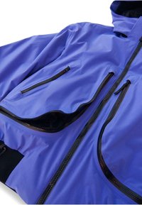 Kék vízálló dzseki sima textúrával, több cipzáras zsebbel és fekete díszítéssel a cipzárokon és a mandzsettákon. Kapucnis kialakítás.