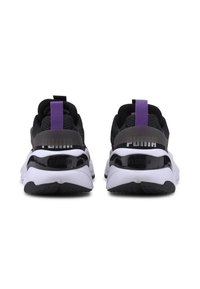 Svarta sneakers med en lila hälflik, överdel i mesh och glänsande svarta detaljer. Tjock vit sula med texturerade detaljer. "PUMA"-logotypen synlig.
