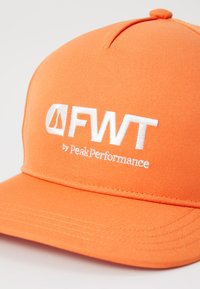 Texturált anyagból készült narancssárga sapka, elöl fehér hímzett "FWT by PeakPerformance" logóval. Strukturált kialakítás, ívelt karimával.