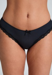Melns rievots bikini ar mežģīņu apdari gar malām. Iezīmējas ar mazu dekoratīvu loku priekšā centrā. Kopumā gluda tekstūra.