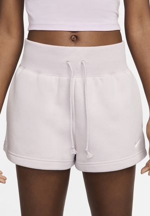 Donna che indossa pantaloncini rosa chiaro a vita alta con coulisse e un top corto abbinato che mostra addome e ombelico.
