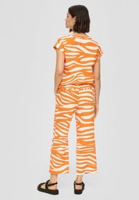 Oranje en witte zebra-gepatenteerde katoenen outfit met een korte mouw top en wijde pijpen, met een relaxte pasvorm en contrasterende tailleband.