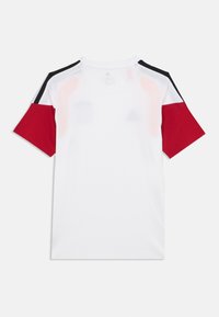 T-shirt à manches courtes avec un corps blanc, des manches rouges et des accents noirs sur les épaules, fabriqué en tissu léger avec une texture lisse.