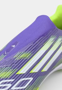 Purple soccer shoe with a sleek design, featuring textured accents and white and green striping. The upper displays a smooth finish.