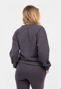 Felpa grigia scura realizzata in morbido tessuto, con vestibilità comoda, polsini a costine e un girocollo pulito. Design semplice, senza motivi.