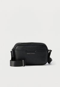 Μαύρο δερμάτινο τσαντάκι Armani Exchange με μπροστινή τσέπη, ασημί φερμουάρ και ρυθμιζόμενο υφασμάτινο λουρί σε απλό φόντο.