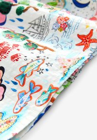 Tejido multicolor con diseños impresos de peces, árboles, botes y estrellas de mar sobre un fondo claro; textura suave, ligero y con patrones vibrantes.