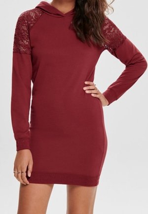 Robe à capuche bordeaux en tissu doux, avec des détails en dentelle sur les épaules, des manches longues et une coupe ajustée avec des accents côtelés.