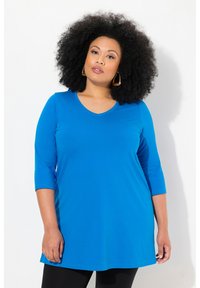 Blauwe tuniektop met driekwart mouwen en een V-hals. Zachte stof met een gladde textuur, met een losse, verlengde pasvorm.