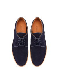 Chaussures habillées en suède bleu marine avec un bout rond, fermeture à lacets et semelle en cuir tan. Texture lisse avec des détails de couture contrastés.