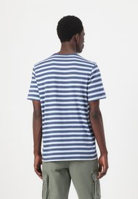 Gestreepte t-shirt met korte mouwen; blauwe en witte horizontale strepen; zachte stof; ronde hals; achteraanzicht; gecombineerd met groene cargo shorts.