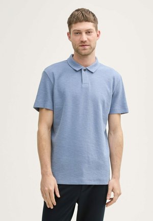 Polo de manga corta en azul claro, tejido texturizado, con cuello y tapeta de dos botones. Corte ligeramente relajado.