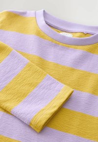 Pull à col rond avec de larges rayures horizontales jaunes et lavande, présentant des manches longues repliées et un tissu tricoté texturé.