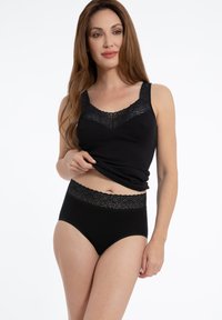 Schwarzes Tanktop mit Spitzenbesatz am Ausschnitt und an den Trägern, kombiniert mit hochgeschnittenen schwarzen Unterhosen, die über einen Spitzenbund verfügen.