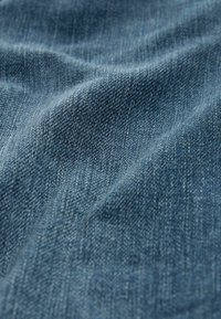 Tejido de denim en azul oscuro, con una textura suave y sutilezas de patrones de tejido en diagonal y tonos de color variados.
