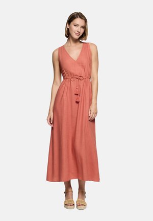 Mujer con un vestido maxi sin mangas color terracota, con escote en V y cinturón con borlas en la cintura, combinado con sandalias de cuña beige.