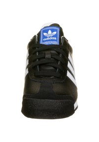 Černá teniska se třemi bílými pruhy, kůže a semišová textura, kulatá špička a modrá logo štítek na jazyku. Pryžová podrážka pro lepší přilnavost.