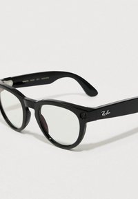 Sorte Ray-Ban solbriller med rektangulære rammer, har mørke linser og en lille kameradetalje foran. Glat plastikoverflade.