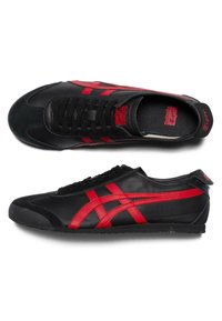 Black athletic shoes with red accents and side stripes, featuring a textile upper, rubber sole, and lace closure. Smooth and textured surfaces.