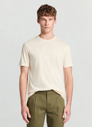 T-shirt beige a maniche corte in tessuto liscio con scollo rotondo, abbinata a pantaloni sartoriali verde oliva. Design semplice e aderente.