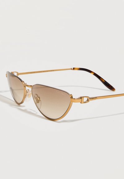 Γυαλιά ηλίου με χρυσό σκελετό σε σχήμα cat-eye, καφέ φακούς με διαβάθμιση και άκρα κλαδιών με σχέδιο από κέλυφος χελώνας σε λευκό φόντο.