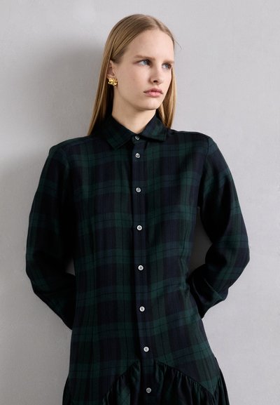 Green and navy plaid shirt dress with a button front, collar, and gathered hem; features long sleeves with buttoned cuffs.