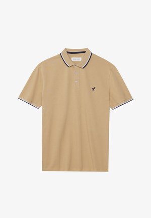 Polo beige en tissu texturé, avec un col rayé noir et blanc, une patte de boutonnage à trois boutons et un petit logo d'oiseau noir.