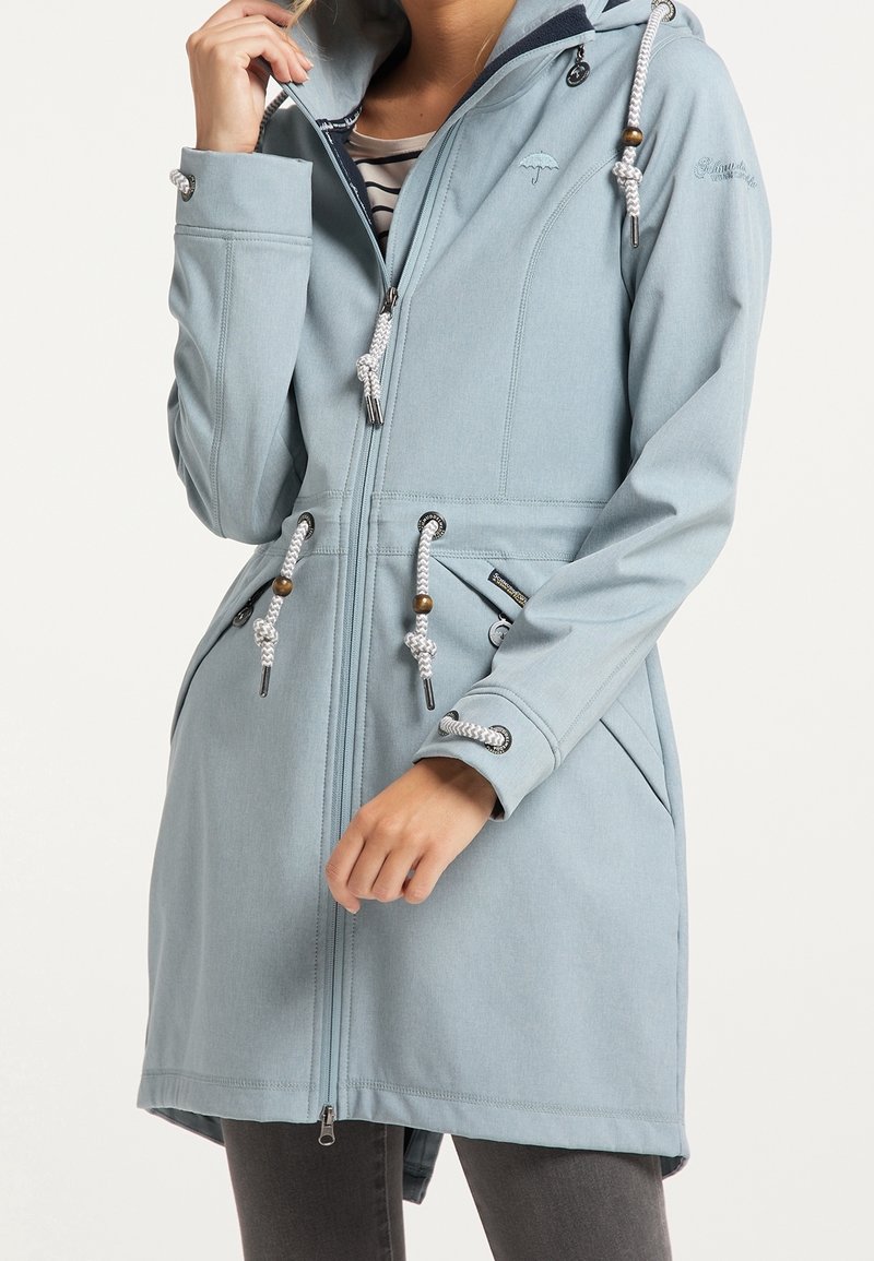 Veste à capuche bleu clair en tissu doux. Comprend une fermeture éclair intégrale, une taille à cordon, deux poches latérales et des accents argentés.