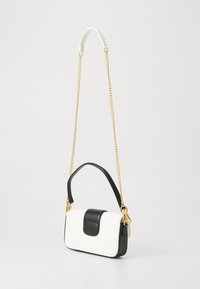 Zwart-witte leren handtas met een ronde vorm, gouden kettingriem en een gladde textuur. Heeft een opvallende zwarte klep sluiting.