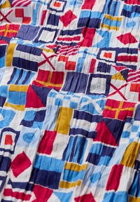Bunt gewebter Stoff mit geometrischen Mustern in Rot, Blau, Gelb und Weiß. Mit Falten und einer strukturierten Oberfläche mit verschiedenen Formen.