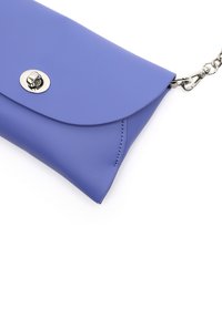 Pochette en simili cuir violet avec un rabat arrondi, fermeture à pression en métal argenté et une bandoulière en chaîne. Texture lisse avec des détails de piqûre discrets.