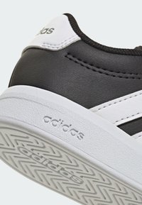 Černá kožená bota s bílými akcenty, vybavená strukturovanou gumovou podrážkou a třemi výraznými bílými pruhy po straně.