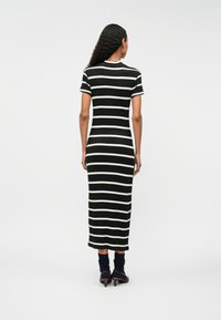 Fekete-fehér csíkos bordás maxi ruha rövid ujjakkal, kerek nyakkivágással és testhez simuló sziluettel, bokaig ér.