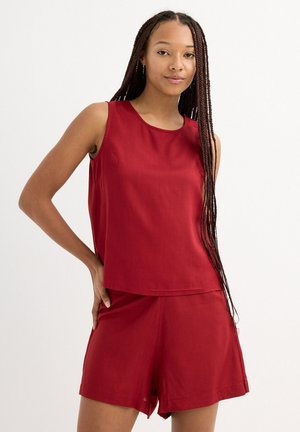 Top sin mangas rojo con escote redondo, combinado con pantalones cortos a juego. Tela suave con un ajuste relajado, sin patrones ni acentos visibles.