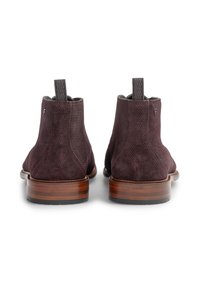 Bottes chevilles en cuir suédé marron avec des panneaux texturés, semelles en cuir et languettes de tirage ; talons empilés en bois avec des rayures horizontales.