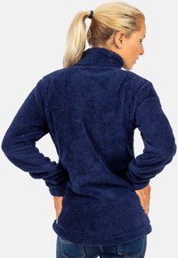 Marineblauwe fleece pullover met een hoge kraag, textuur, zacht materiaal en lange mouwen. Beschikt over een gebogen zoom en een ontspannen pasvorm.