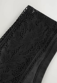 Ciorap de mână din dantelă neagră cu un model floral complex, textură moale și o margine uniformă de culoare neagră. Bandă elastică în partea de sus pentru o fixare sigură.