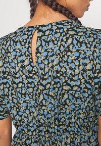 Vestido de estampado floral con base negra, que presenta patrones en azul y beige, mangas cortas y un detalle de ojal en el cuello de la espalda.