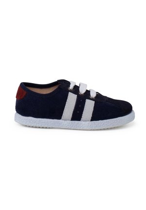 Zapato de ante azul marino con rayas blancas, suela texturizada blanca y acento en el talón rojo. Presenta un diseño clásico de cordones y forma de punta redondeada.