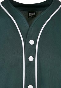 Maillot de sport vert foncé à boutons avec passepoil blanc le long des bords et trois boutons-pression blancs visibles.